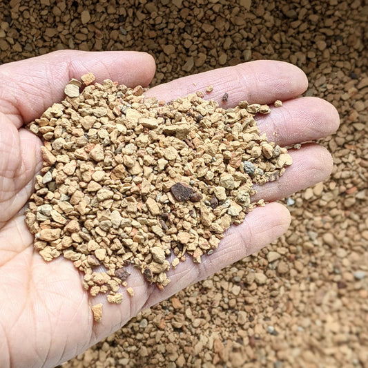 Close-up of calcined clay held in a person's hand, showcasing its texture and granules.